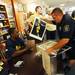 Ann Arbor police officer Chuck Graham pulls out a poster for Michigan football star Desmond Howard to sign during an autograph signing at the M Den on Friday. The poster, along with a second larger version, will be auctioned off during a charity for the late Ann Arbor police officer Vada Murray.  Melanie Maxwell I AnnArbor.com